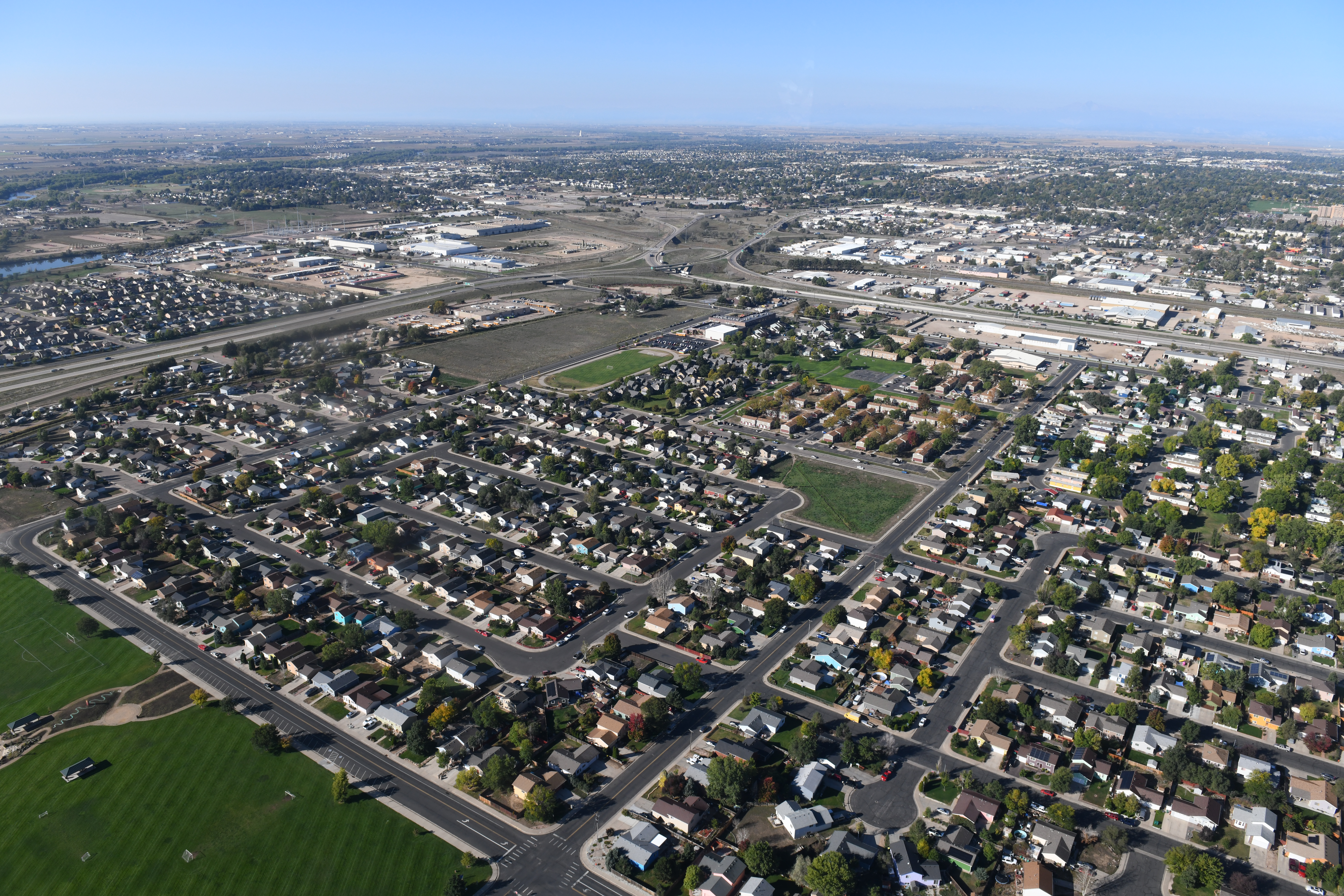 Aerial view of residential housing development, with retail and commercial properties in the background. 