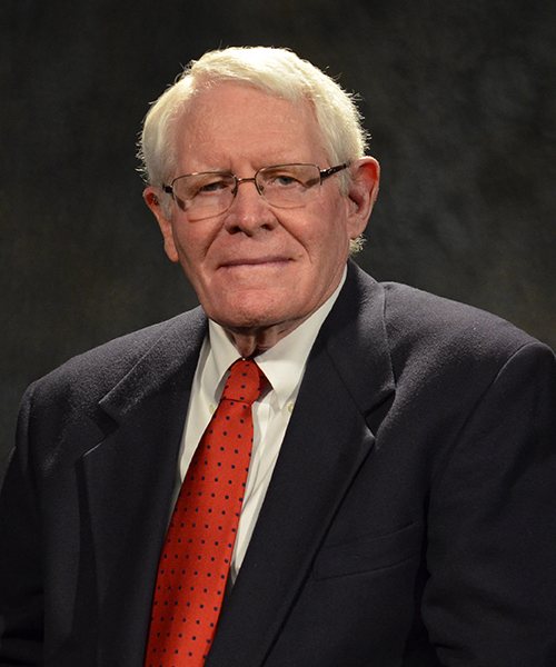 A formal image of Harold Evans, showcasing professional attire and neutral background.