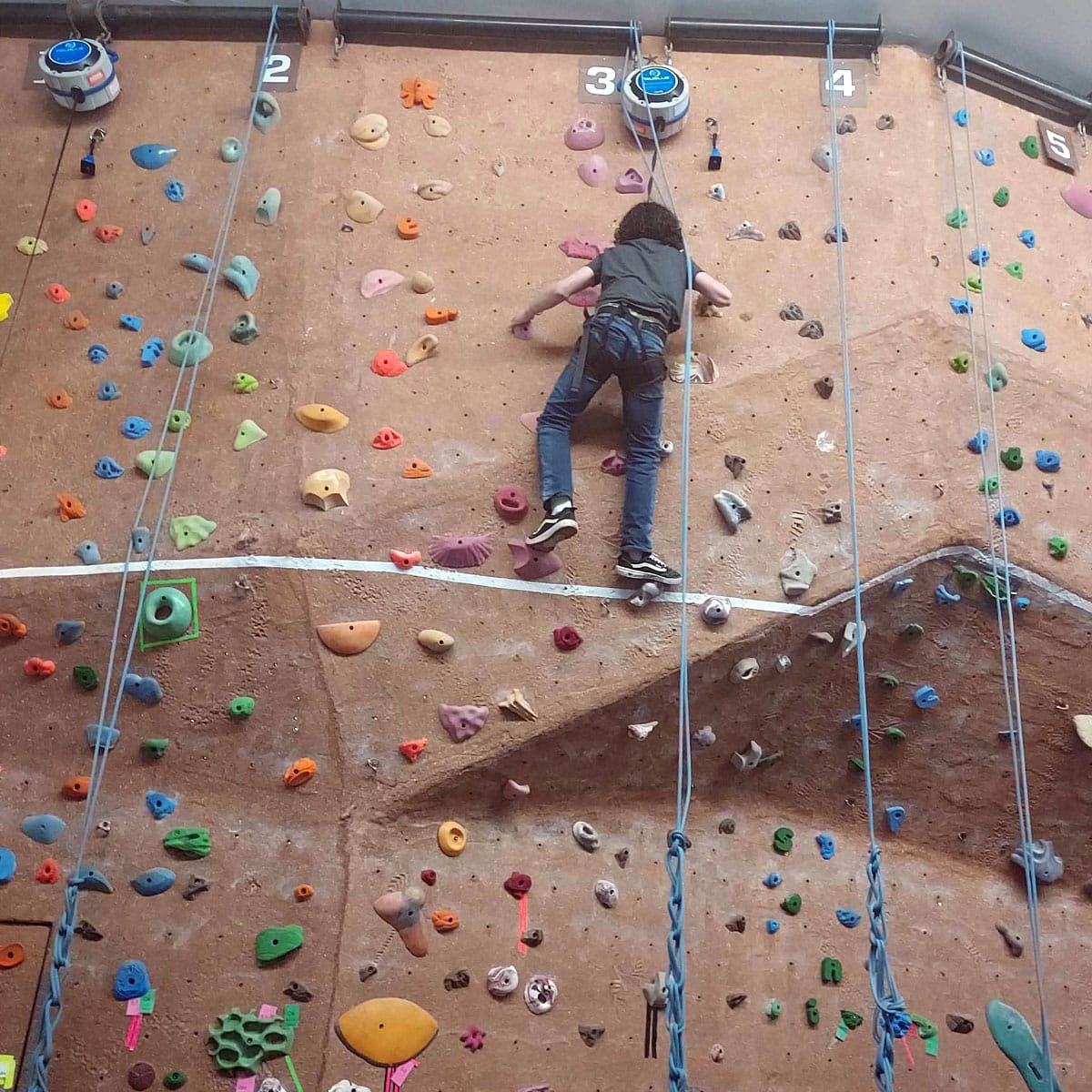 A young climber scaling the wall at Greeley Recreation Center, showcasing physical activity and community engagement.