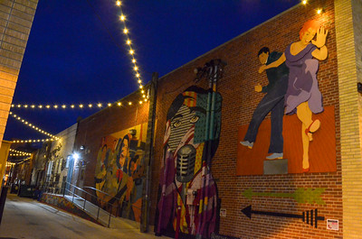 A vibrant alleyway featuring colorful murals and string lights, showcasing community creativity.