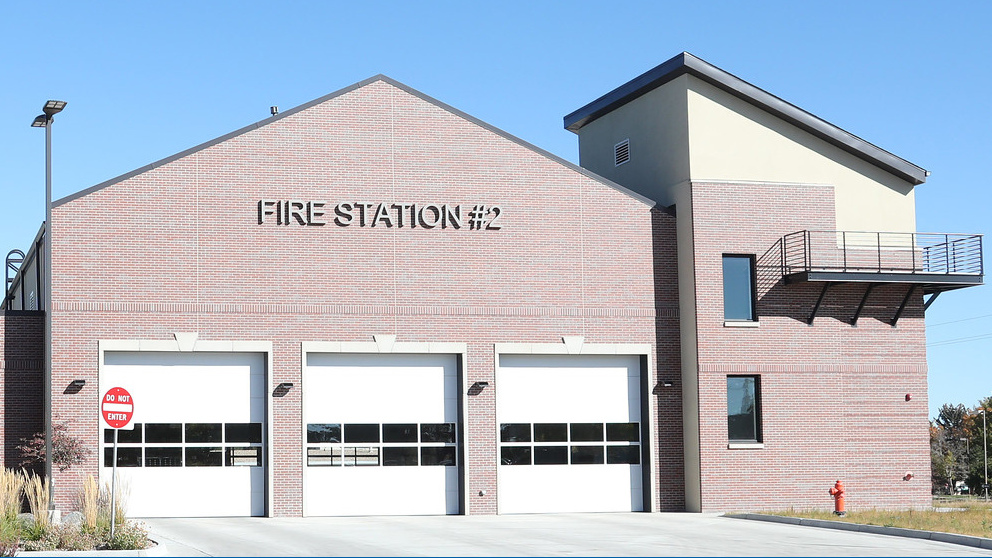 A bright and modern fire station with a brick exterior and large garage doors, surrounded by landscaping.