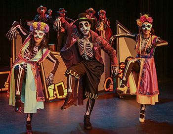 Colorful dancers in skeleton attire showcasing traditional culture on stage.