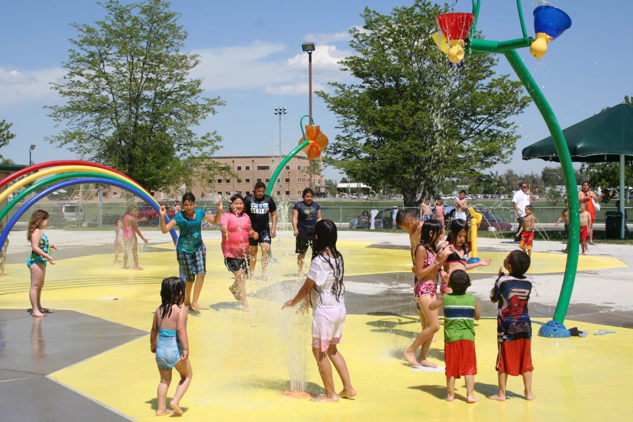 Children enjoying water activities at a vibrant community splash park on a sunny day.