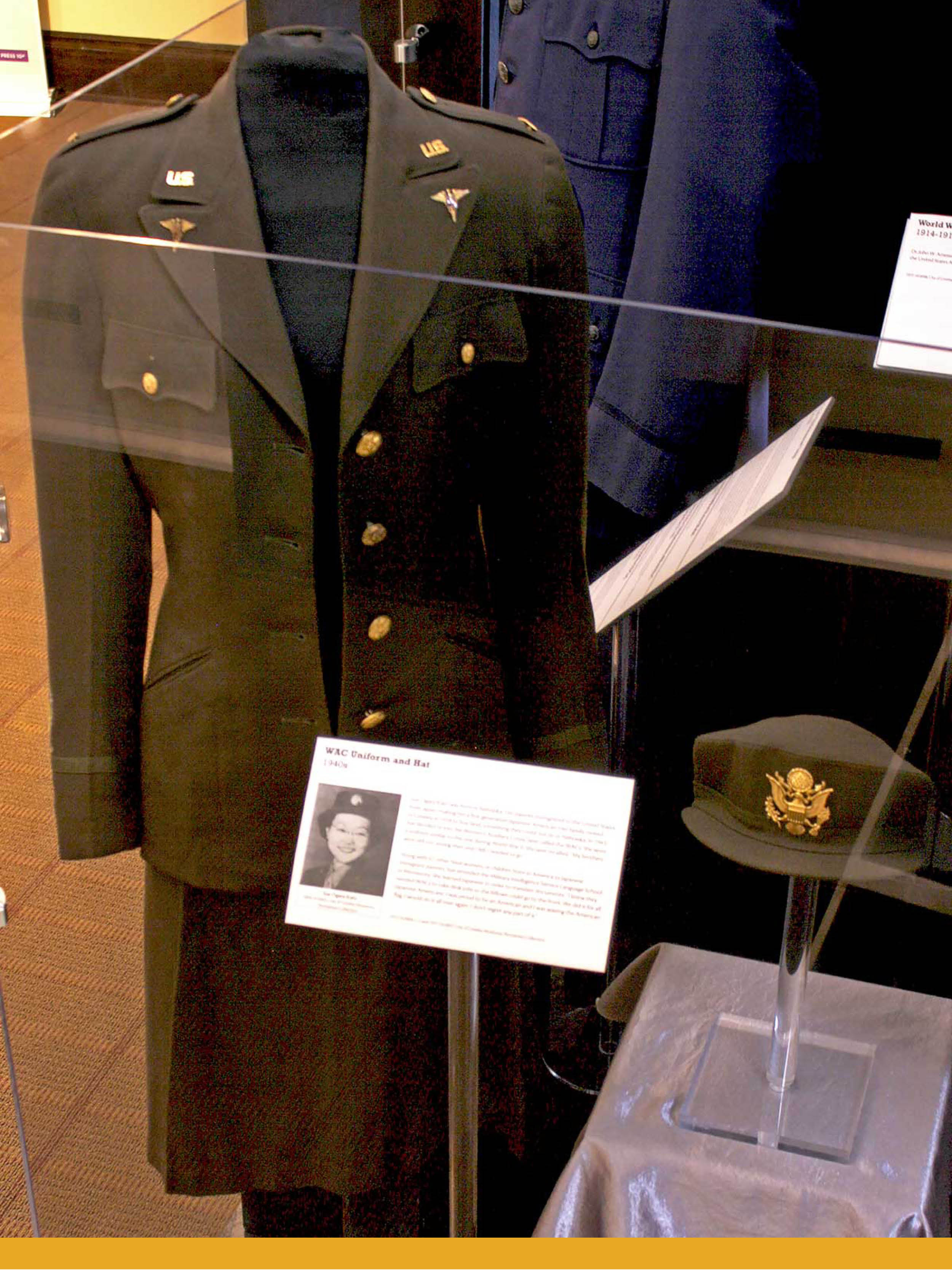 A mannequin wearing a women's military uniform. The uniform’s hat is displayed next to it.