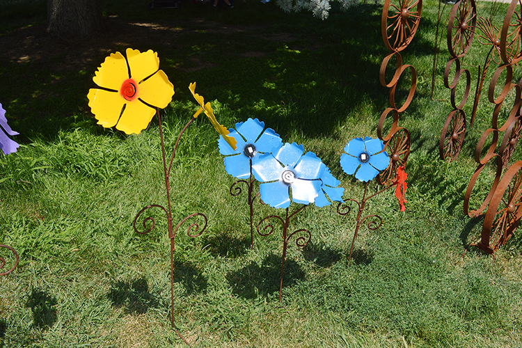 A vibrant display of handcrafted metal flowers set against lush green grass during Arts Picnic 2023.