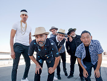 A group of musicians photographed outdoors, suggesting a press release event promoting a concert or activity.