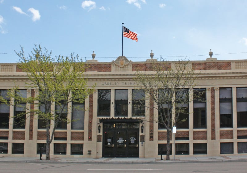 A historic building in Greeley, featuring classical architecture and an American flag prominently displayed.