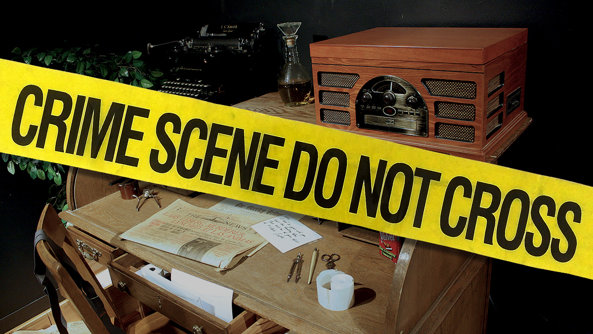 Roll-top desk with various historic items on it including a newspaper, a typewriter, a radio, and writing implements. Do Not Cross crime scene tape displays in front of the image