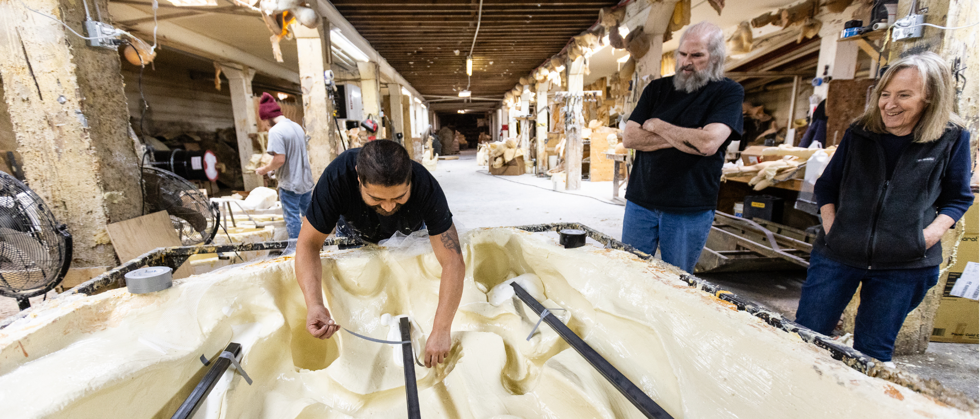 Photos at Distortions Unlimited with three employees building a large Halloween prop and their manufacturing warehouse in the background.