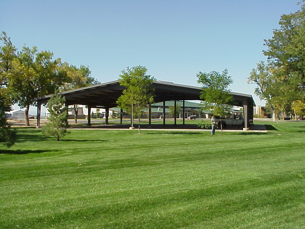 On a sunny summer day, the Poudre River Pavilion stands empty except for a pickup truck and a man tending a tree nearby