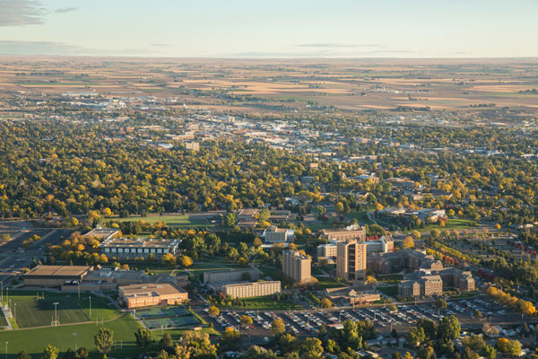 Aerial image capturing the expansive University of Northern Colorado campus nestled within the cityscape of Greeley, surrounded by greenery and urban development.