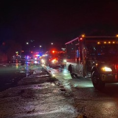 Emergency response vehicles are actively addressing flooding in Greeley at night. Streets are wet and illuminated by vehicle lights.