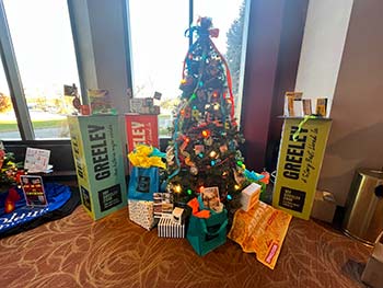 A festive holiday tree surrounded by colorful decoration showcasing the local spirit of Greeley.