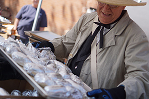 Person showcasing a tray of wrapped potatoes during a community festival event.