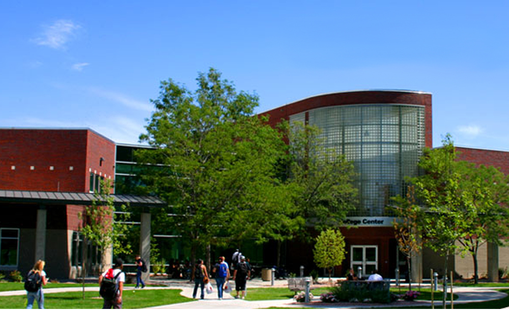A vibrant scene of Aims Community College's campus showcasing modern architecture and students engaging in activities under a clear blue sky.