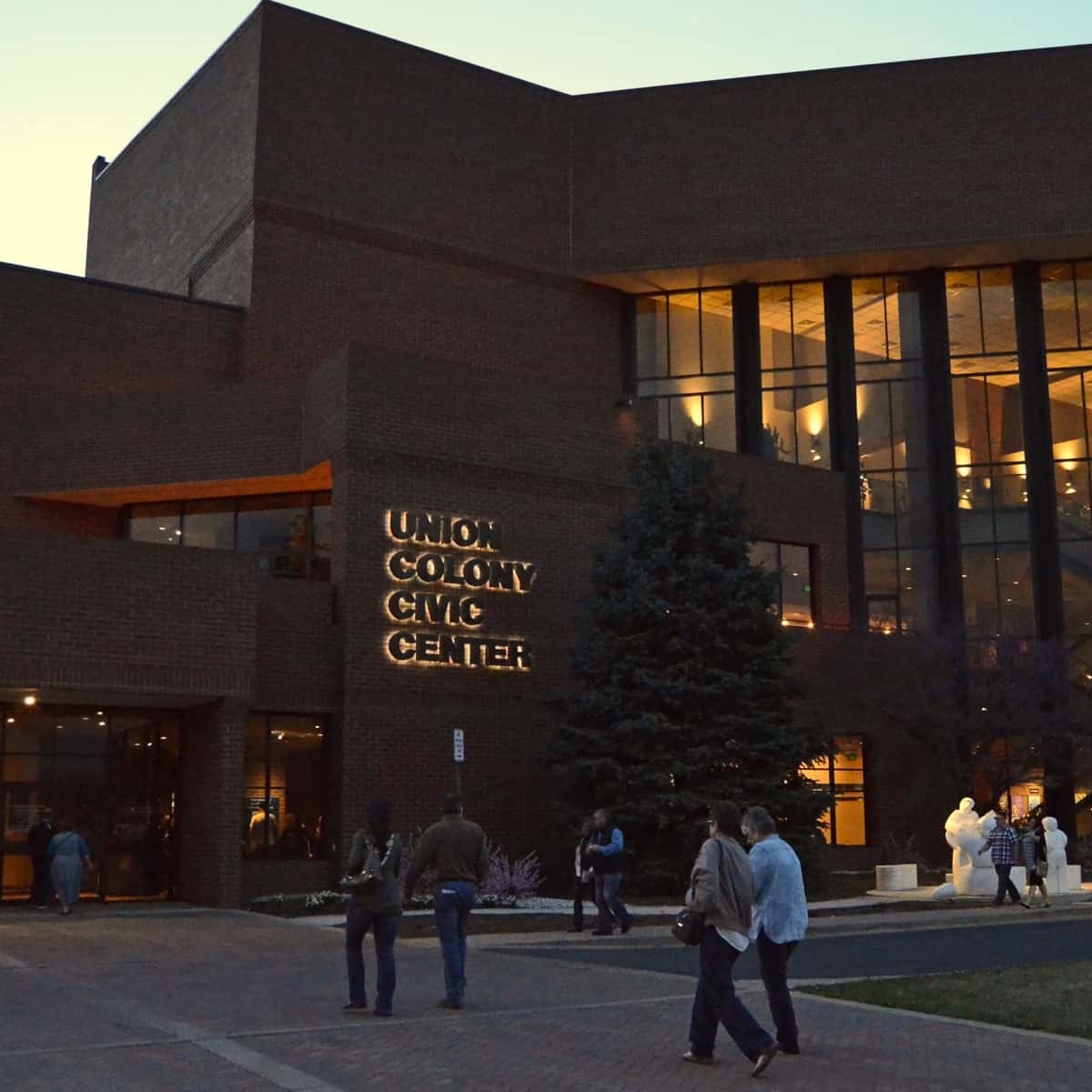Exterior view of the Union Colony Civic Center with people walking towards the entrance during an evening event.