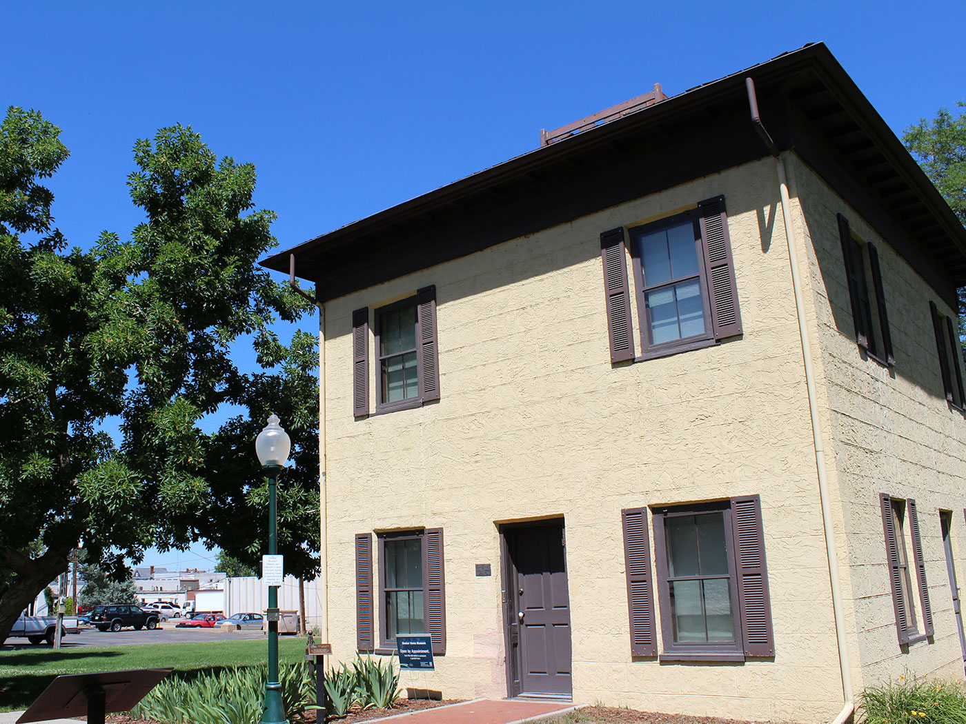 Front exterior view of a two-story house from the 1870s built out of adobe