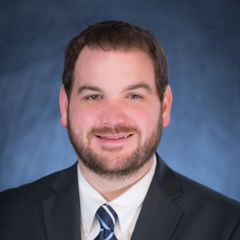 Professional portrait with a blurred face featuring formal attire against a blue background.