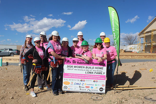 City employees stand smiling around the “Women Build” sign in their personal protective equipment