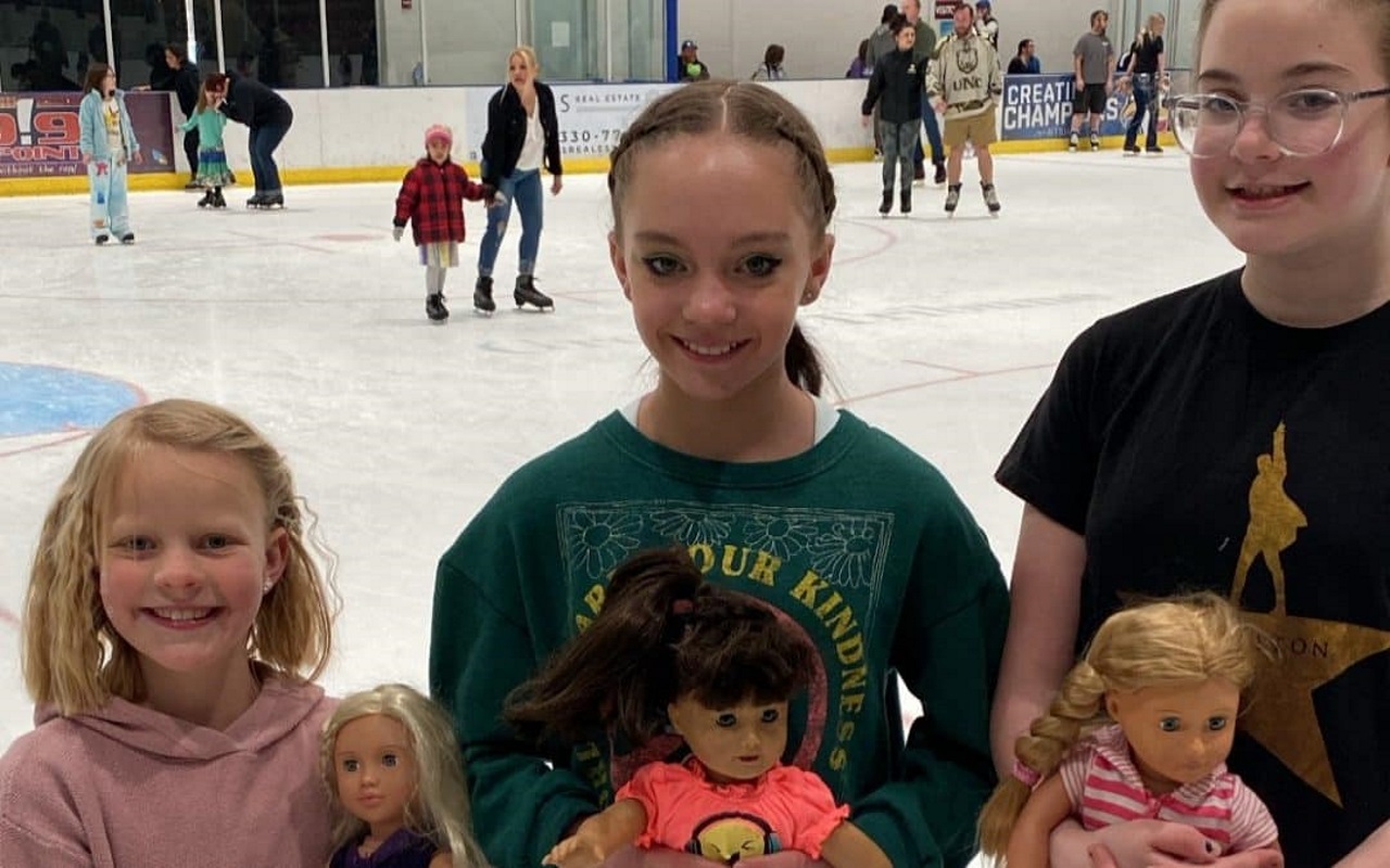 Three girls post with American Girl Dolls at the American Girl Doll Skate event