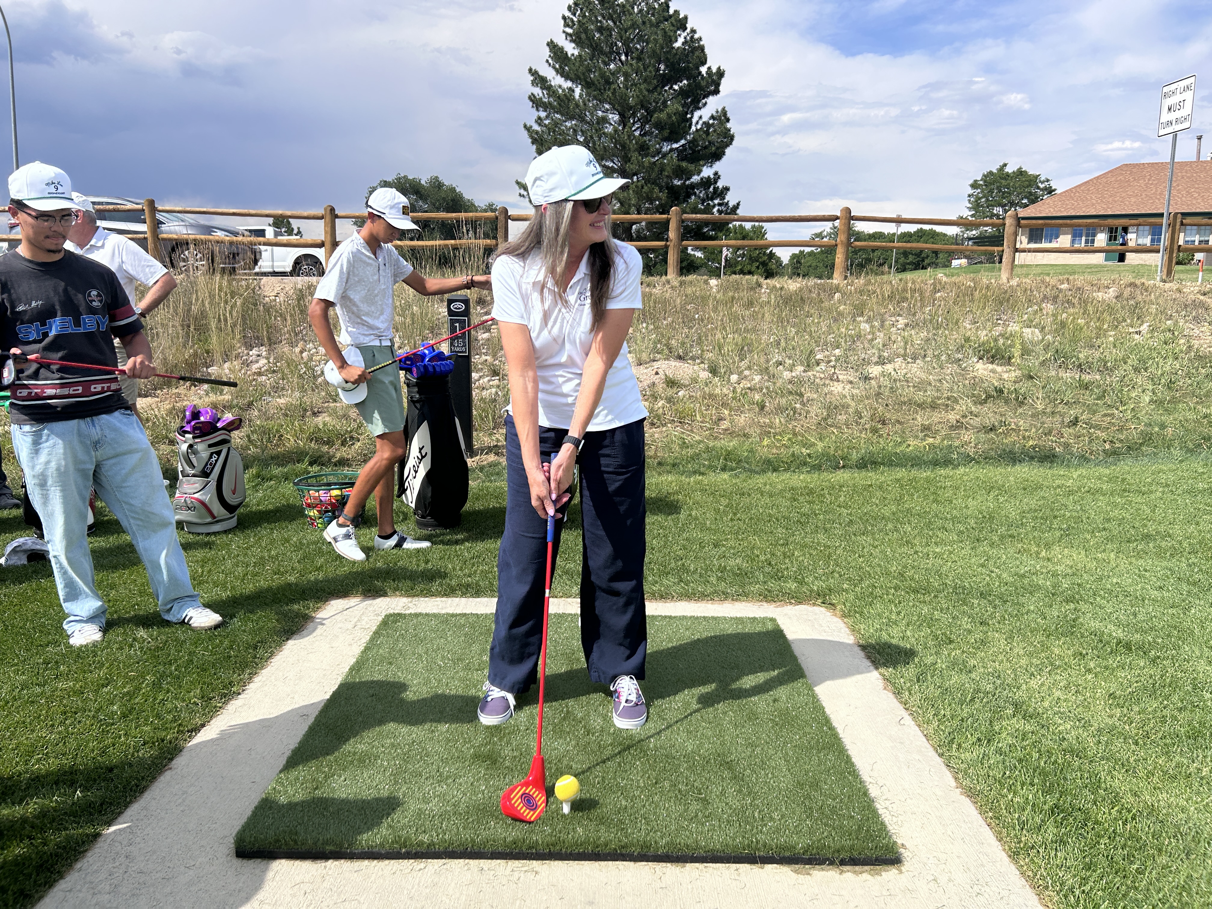 Culture, Parks, and Recreation Director Diana Frick standing at address over a snag ball on a turf tee mat during the Mike Lee 9 opening ceremony at Boomerang Links Golf Course.