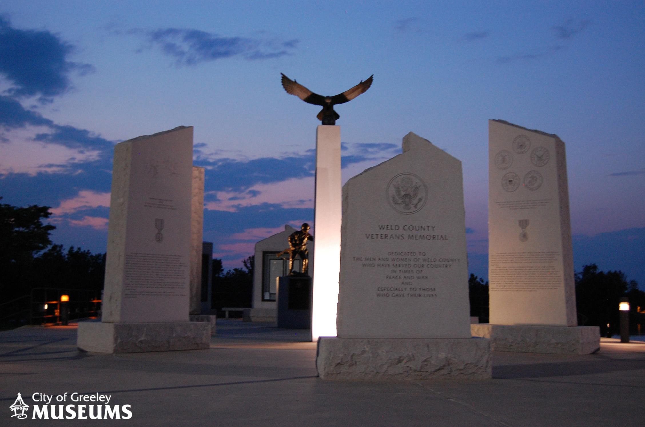 Image of stone pillars and statues at the Veterans Memorial at sunset