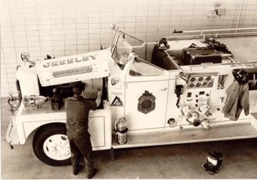 A mechanic performing maintenance on a Greeley fire truck inside a station garage circa 1954.