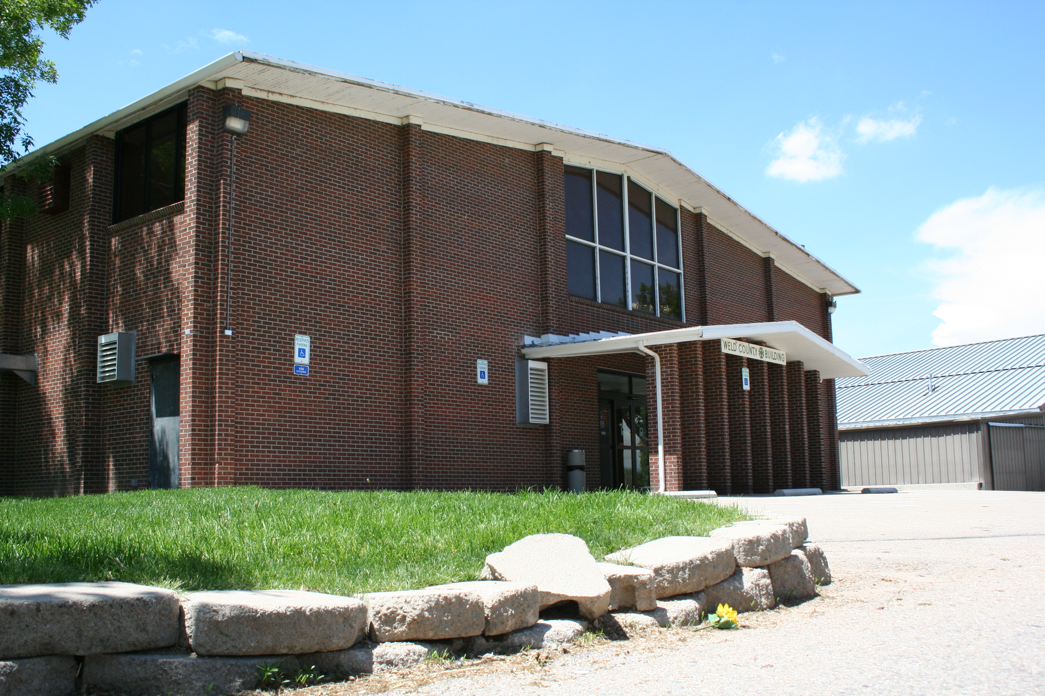 Brick exterior of the 4H Building entrance with signage that reads Weld County Building