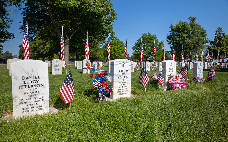 Gravestones of soldiers are interspersed with floral arrangements and American Flags