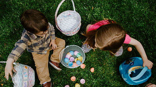Children participating in an Easter egg hunt on a sunny day.