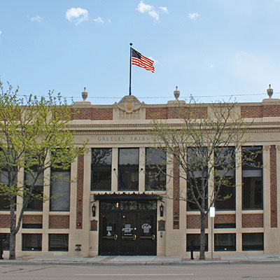 A historic building in Greeley, featuring classical architecture and an American flag prominently displayed.