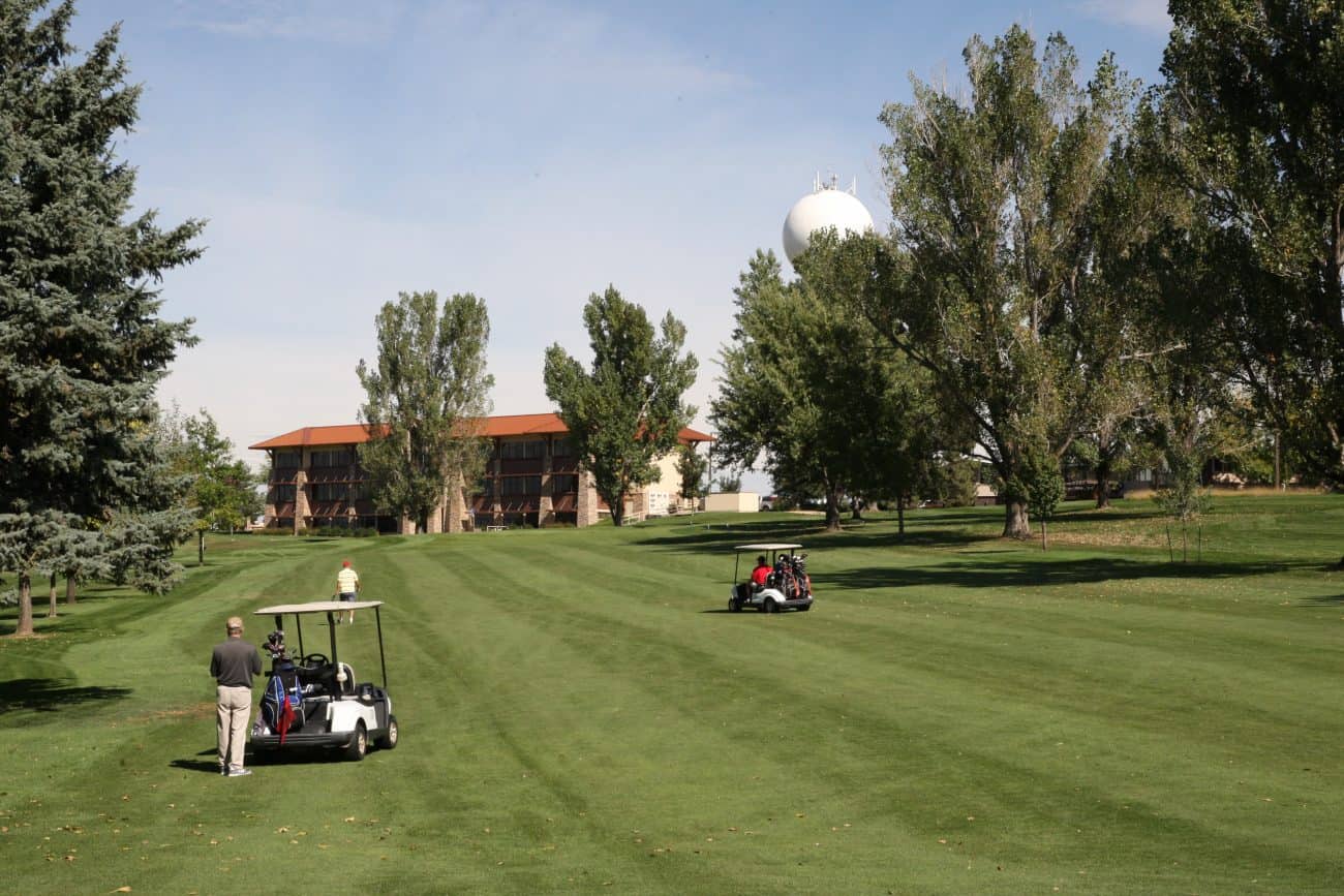 A serene golf course at Highland Hills with individuals enjoying a relaxing day using golf carts among lush greenery.